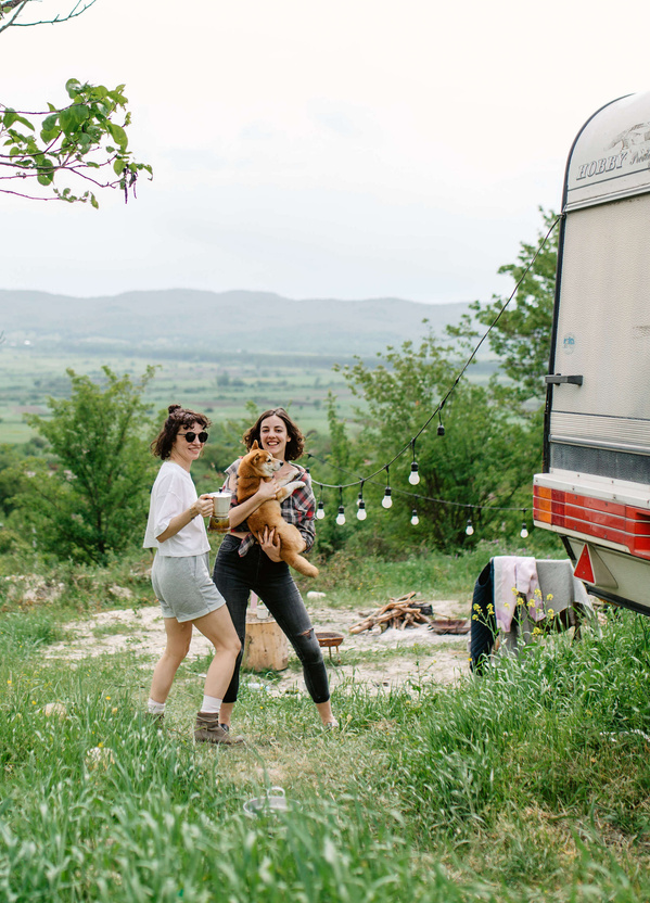 Two Women Playing with Their Dog in a Campsite